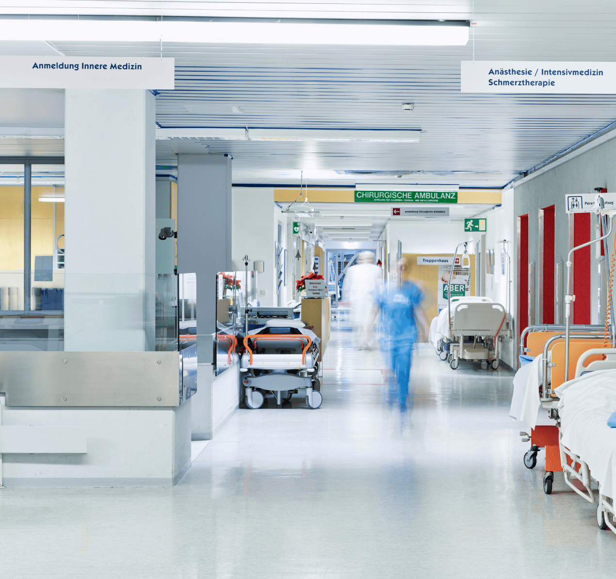 Blick in einen Krankenhausflur. Am Rand stehen Krankenhausbetten.
